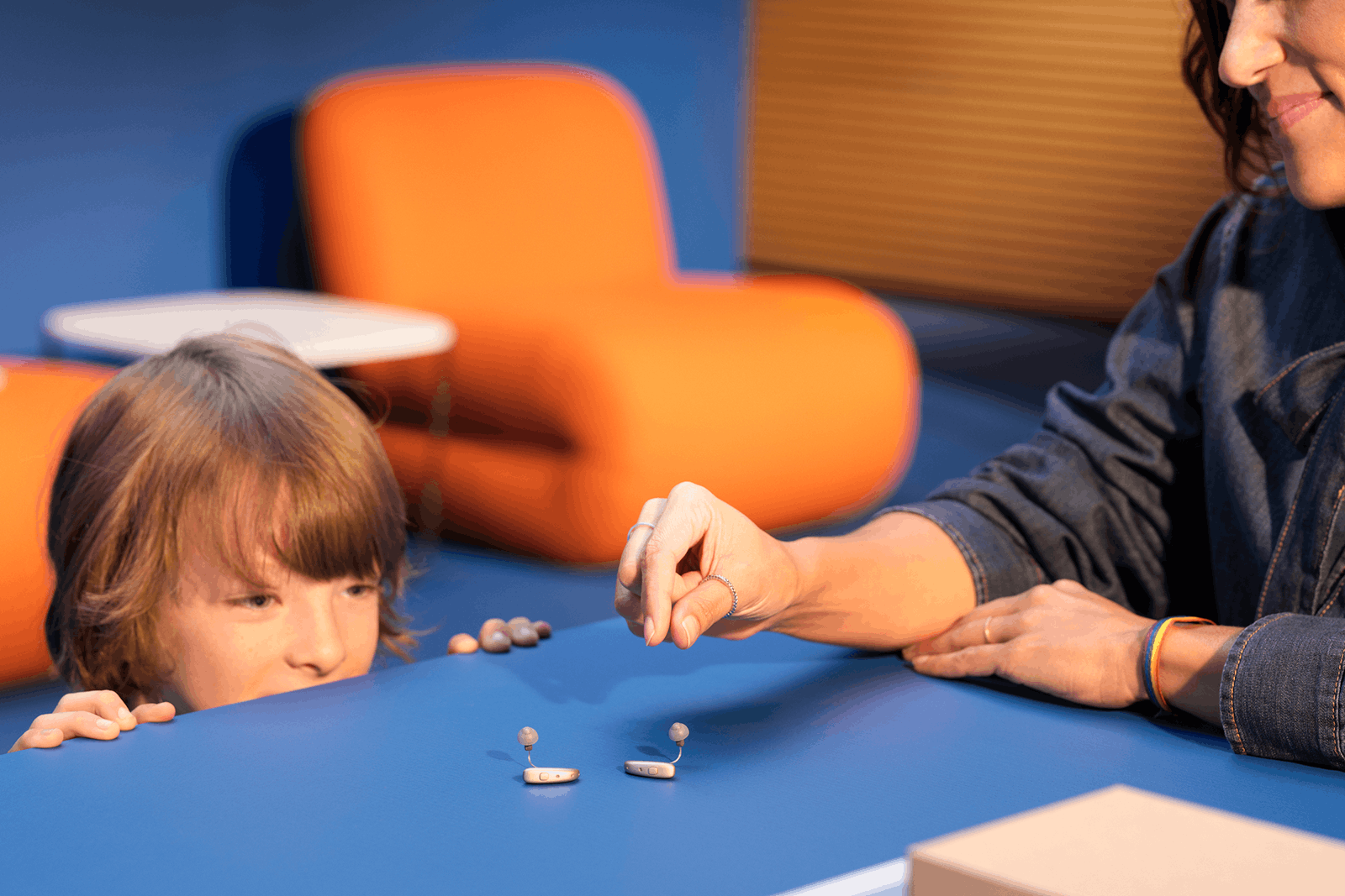 Parent and child looking at hearing aids on the table