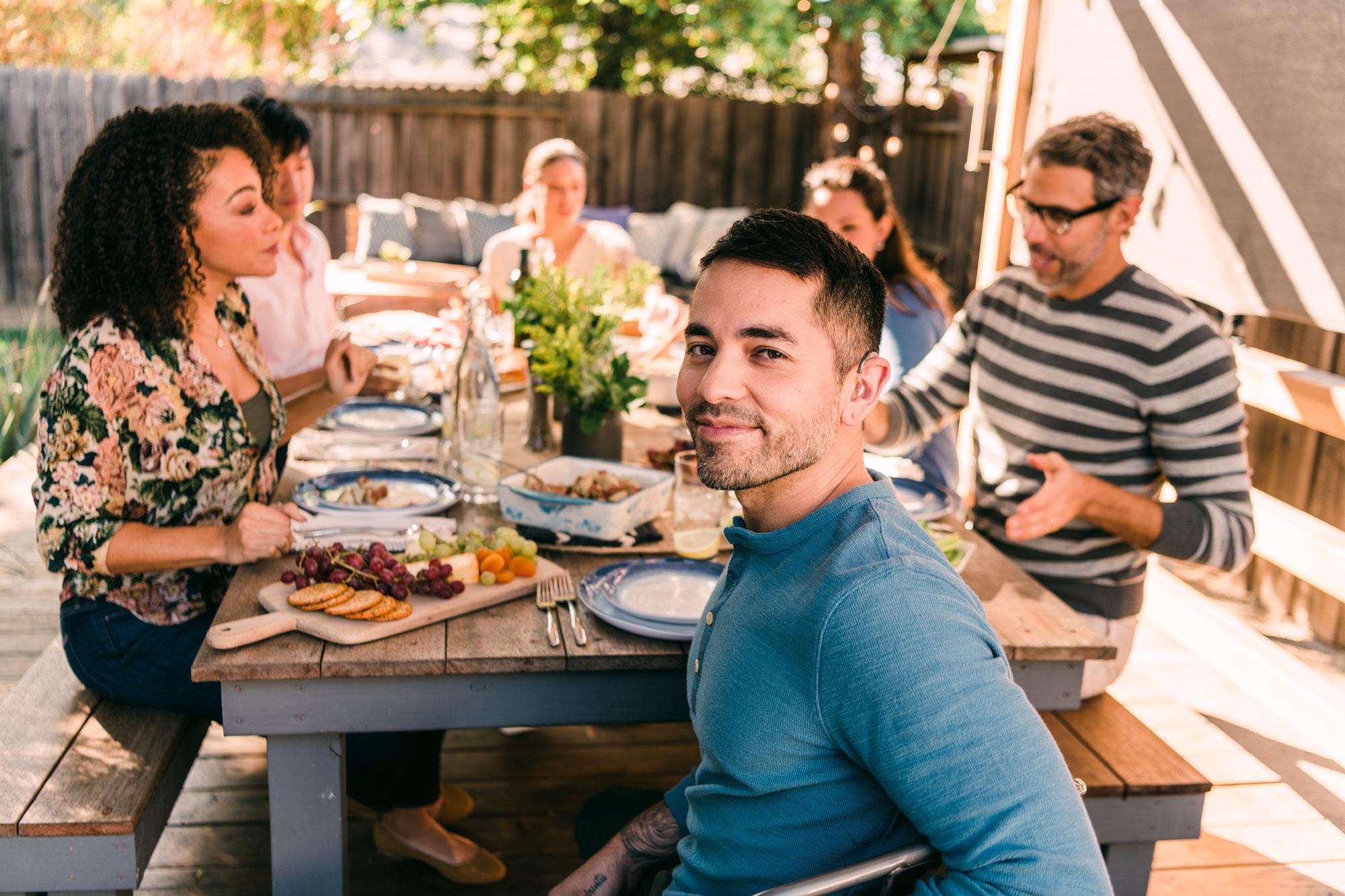 Man wearing hearing aids for severe-to-profound hearing loss and enjoy outdoor party with friends