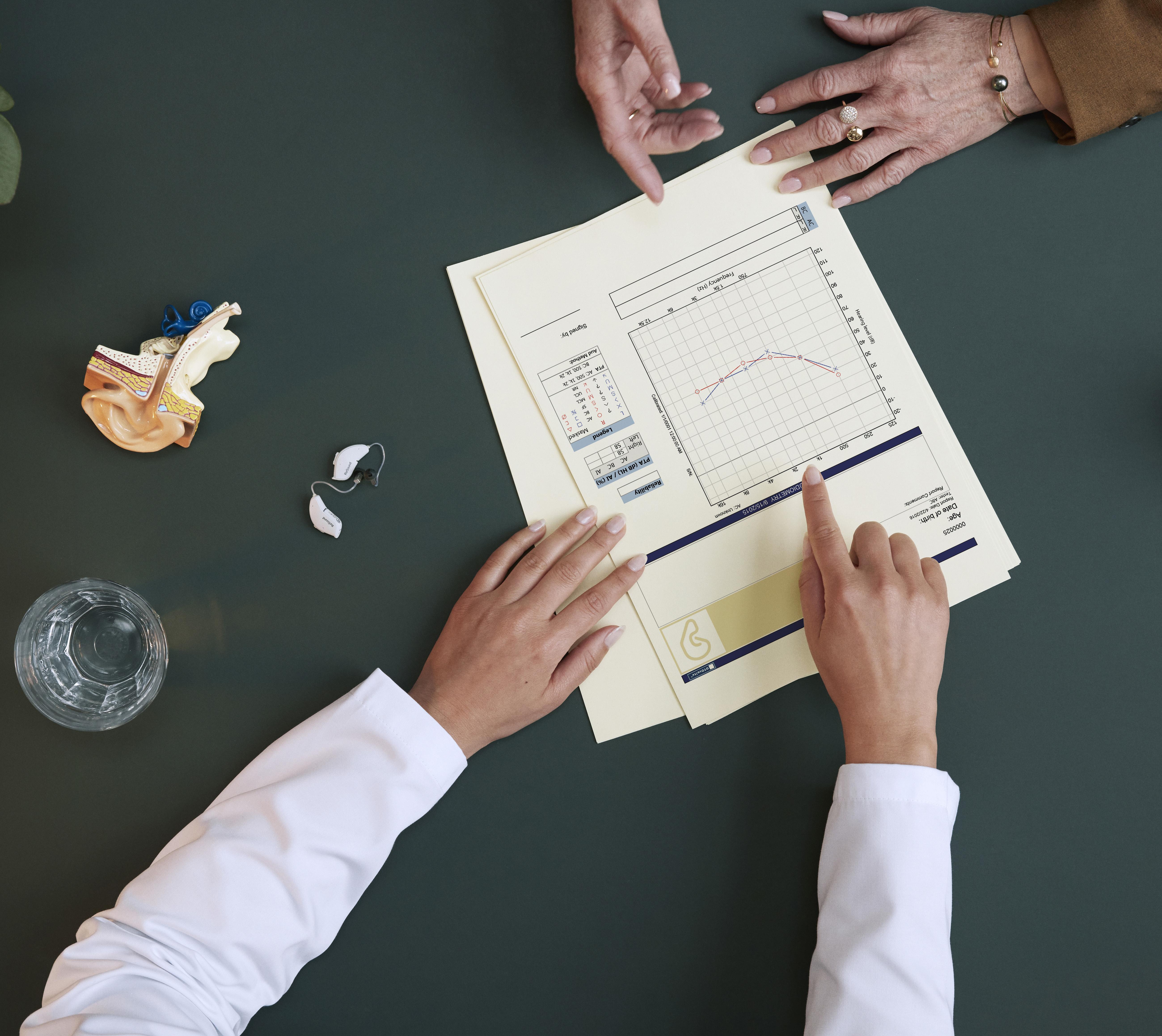 Hearing care professional advising a patient and showing an audiogram.