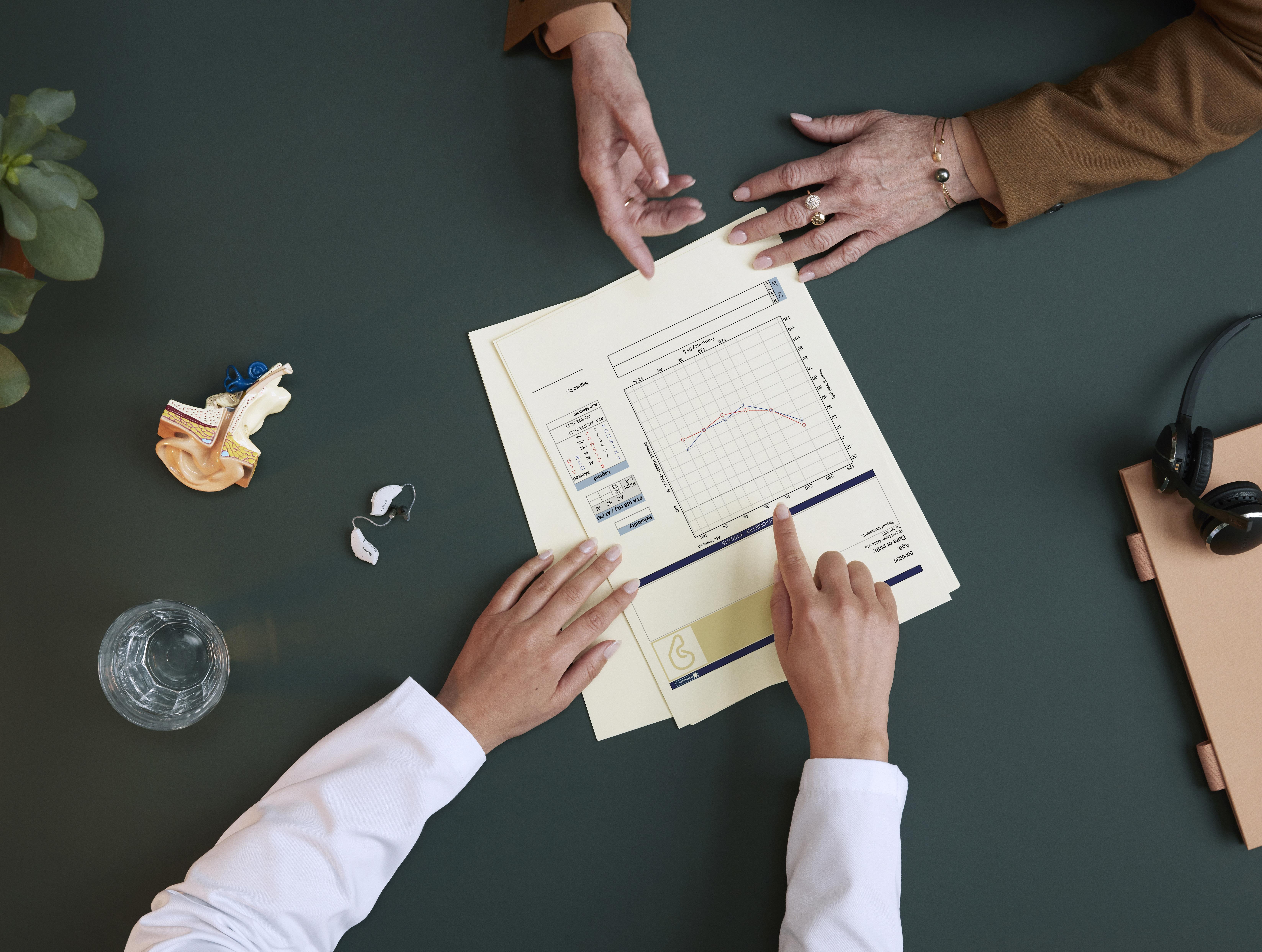 Hearing care professional advising a patient and showing an audiogram.