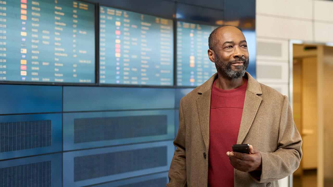 Une femme souriante appuie sur le bouton de son aide auditive ReSound
