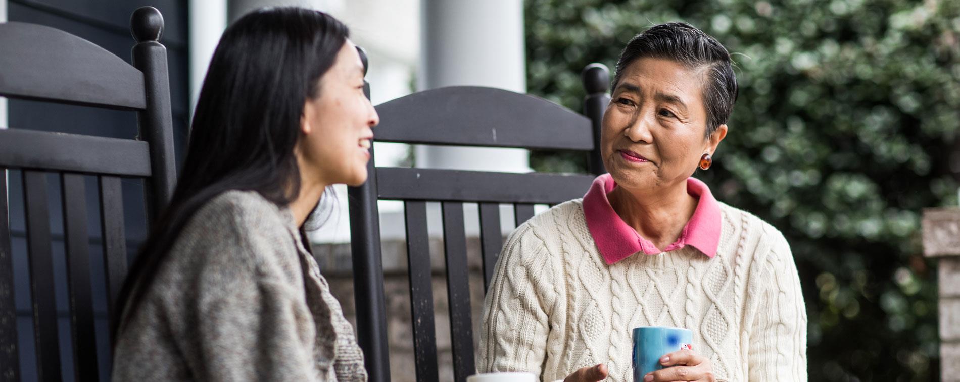 Adult woman talking on front porch with senior mother, a ReSound Key user