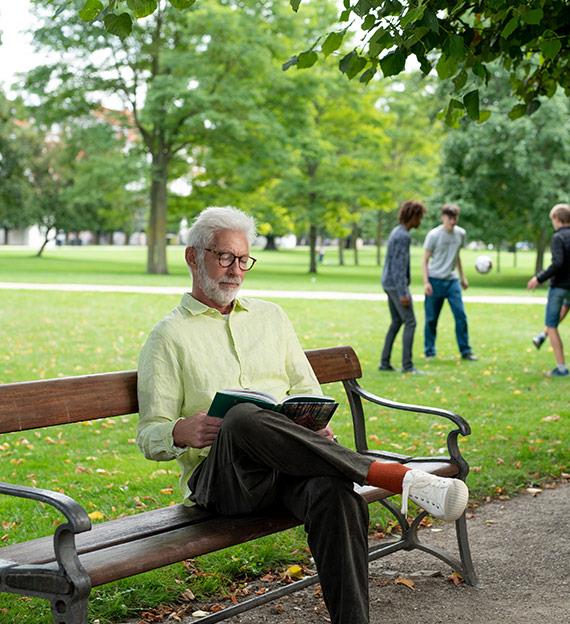 Man reading on a bench in a park